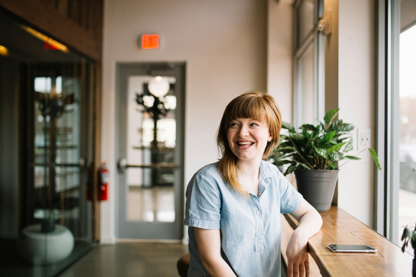 Smiling woman sitting by a window, casual professional portrait