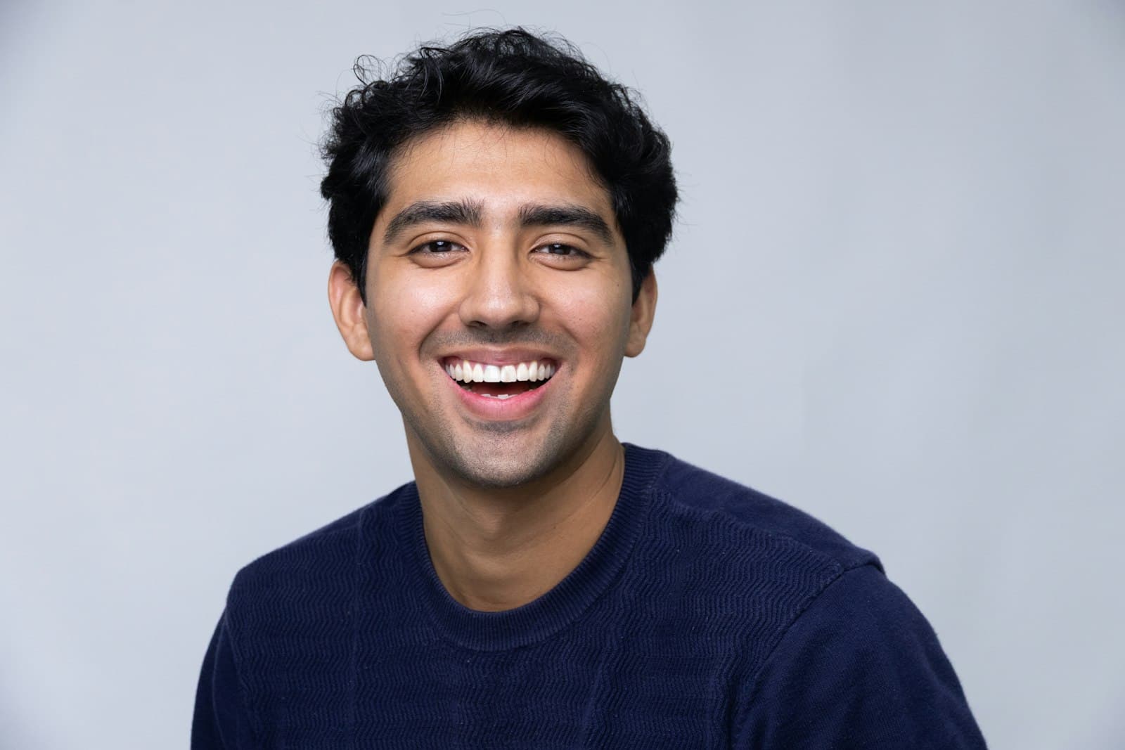 Smiling young man in a dark blue sweater, studio portrait